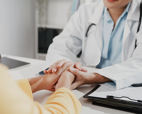 Eine Ärtztin hält die Hand einer Frau – vitaL