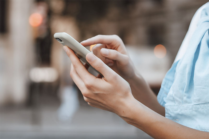 Eine Person hält ein Smartphone in der Hand und tippt mit dem Finger aufs Display